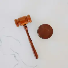 Drewniany młotek sędziowski i okrągły drewniany blok na białym tle.