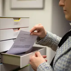 Kobieta przegląda dokumenty w szufladach biurka.